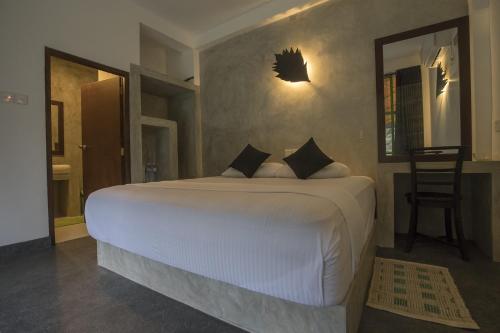a bedroom with a large white bed and a chair at Sinharaja Forest Edge in Deniyaya