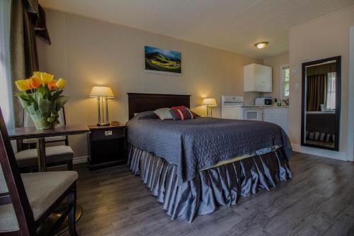 a bedroom with a bed and a table with a vase of flowers at The White Horse Motel in Charlottetown