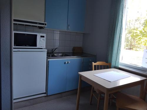 cocina con armarios azules, mesa y microondas en Nalles Gästhem, en Eckerö