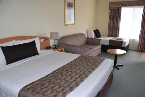 a hotel room with a large bed and a couch at Best Western Coachman's Inn Motel in Bathurst