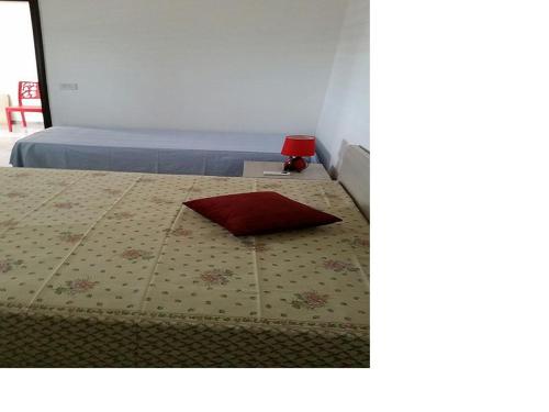 a bedroom with a bed with a red pillow on it at Casa Vacanza Via Lazio in Torre Lapillo