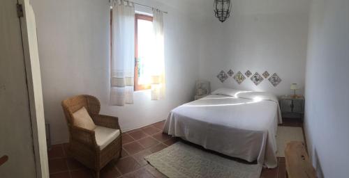 1 dormitorio blanco con 1 cama y 1 silla en Casa Eden beach, en Sorso