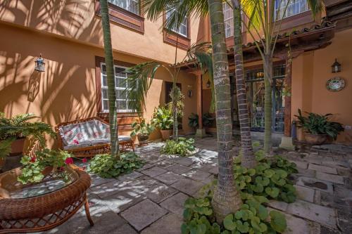 a patio with palm trees and a bench in front of a building at Hotel Emblemático San Marcos in Icod de los Vinos