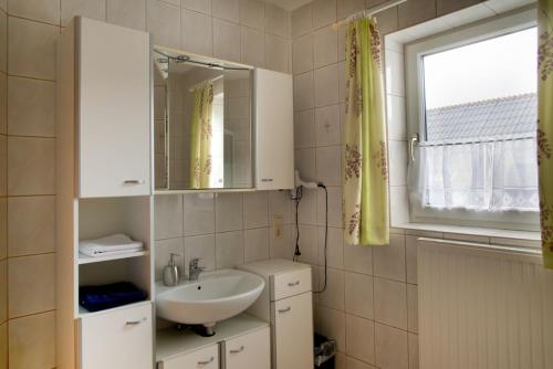 ein Bad mit einem Waschbecken, einem Spiegel und einem Fenster in der Unterkunft Ferienwohnung Märzinger in Ulrichsberg