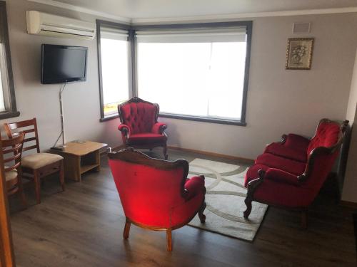 a living room with red chairs and a flat screen tv at Waratah Falls Holiday Unit in Waratah