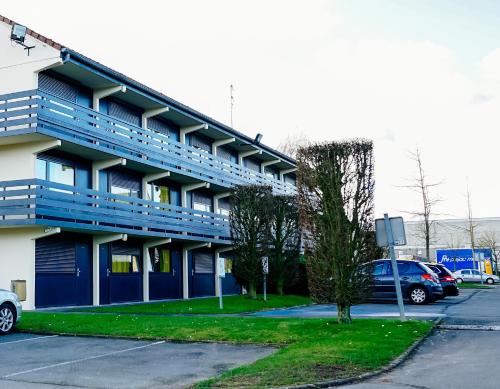 a blue building with cars parked in a parking lot at Kyriad Lille - Roncq in Roncq