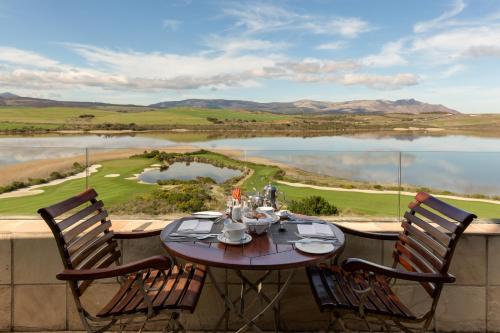 a table and chairs on a balcony with a view of a lake at Arabella Hotel, Golf and Spa in Kleinmond