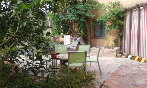een patio met een tafel en stoelen in een tuin bij Atelier Pasquer in Fitou