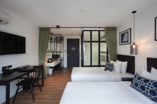 ein Hotelzimmer mit 2 Betten, einem Schreibtisch und einem Computer in der Unterkunft Oriental Heritage Residence in Bangkok