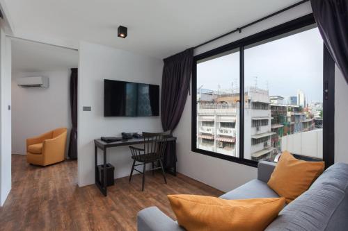 a living room with a couch and a large window at Oriental Heritage Hotel in Bangkok