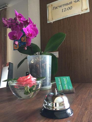 a vase of flowers on a table with a key at Green Hotel in Almaty