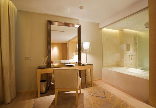 a bathroom with a desk with a mirror and a tub at City Viva Hotel Macau-Fomerly Hotel Million Dragon Macau in Macau