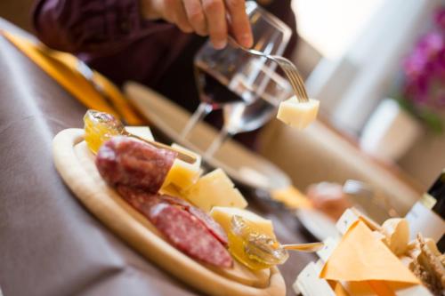 a person is preparing a hot dog with sausage and cheese at Hotel Angelo in Andalo