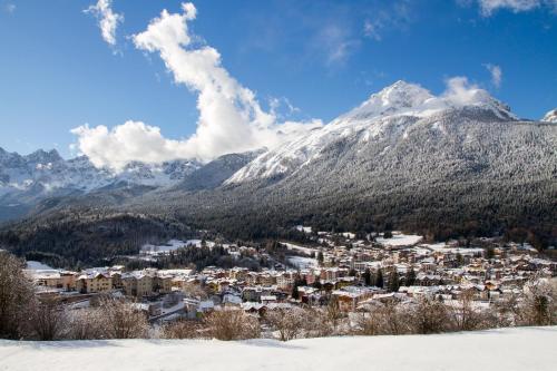 a town in the snow with a snow covered mountain at Hotel Angelo in Andalo