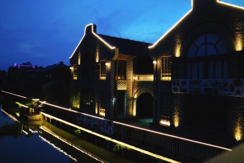 an old building with lights on the water at night at Lin Yin Art Hotel Shanghai（Pudong airport） in Shanghai