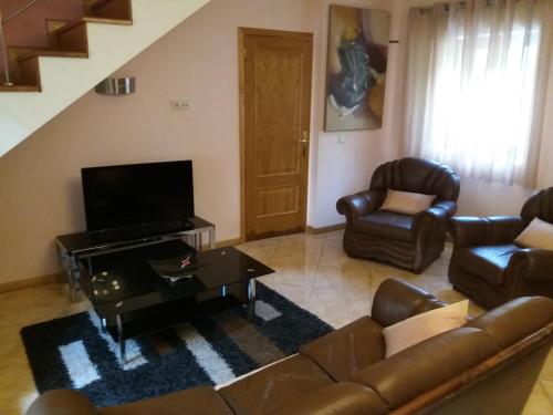 uma sala de estar com um sofá e cadeiras e uma televisão em Casa Dina Doceira no Gerês