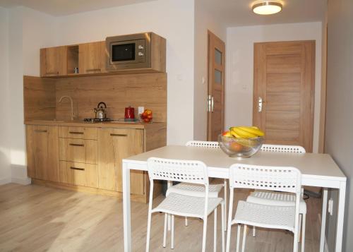 a kitchen with a white table and white chairs at Jaskółka - pokoje i apartament przy plaży in Olsztyn