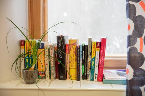a row of books on a window sill with a plant at The Yard Hostel in Helsinki