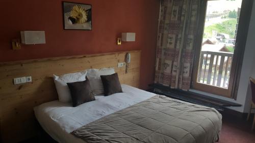 a bedroom with a bed with pillows and a window at Hôtel L'Escale Blanche in Les Orres
