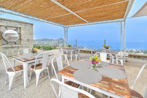 a patio with tables and chairs and the ocean at Tenuta C'est la Vie in Ischia