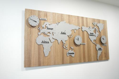 a wooden world map with clocks on a wall at For You Hostel in Yeosu