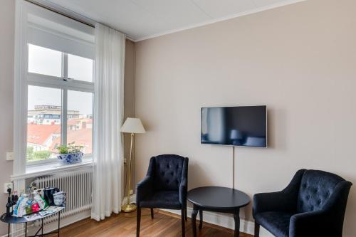 a room with two chairs and a table and a tv at Grand Hotel Jonkoping, BW Signature Collection in Jönköping