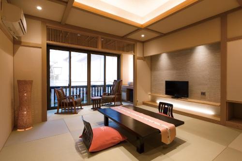 a living room with a table and a tv at Kizukuri no Yado Hashizuya in Misasa