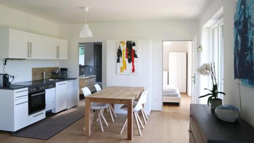 cocina con mesa de madera y armarios blancos en Appartement Belvedere, en Keutschach am See