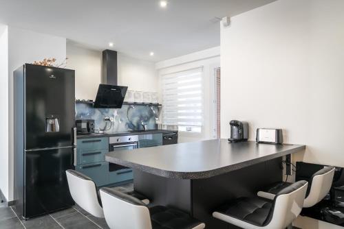 Il comprend une cuisine équipée d'un réfrigérateur noir et d'un comptoir. dans l'établissement Calme & Spacieux - 100m2 - Gare St-Roch, à Montpellier