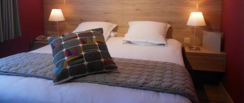 a bedroom with a large bed with pillows and two lamps at Hostellerie du Peiffeschof, The Originals Relais in Arlon