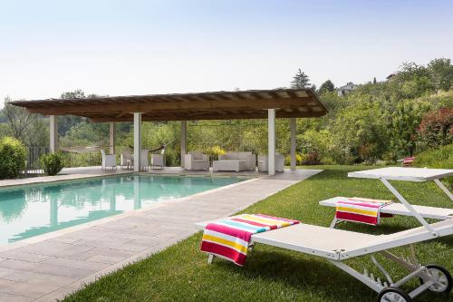a pool with two lounge chairs and a pavilion at Il Sambuco Innamorato in Acqui Terme