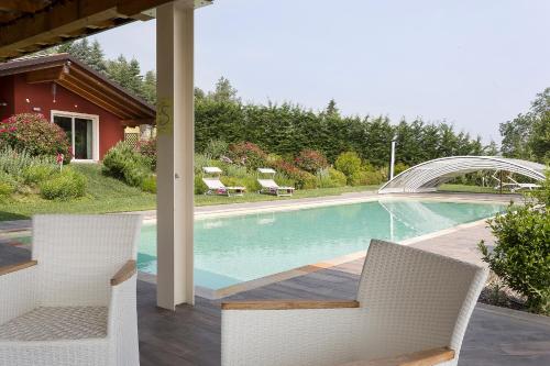 a swimming pool with two chairs next to a house at Il Sambuco Innamorato in Acqui Terme
