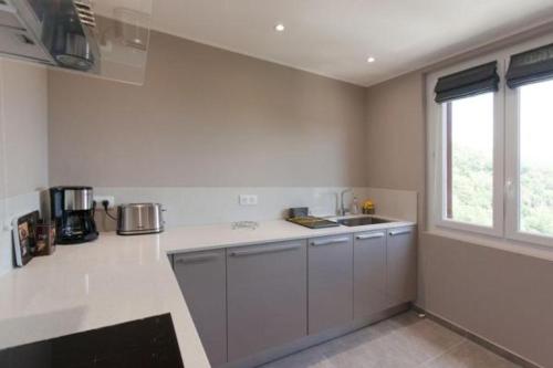 a white kitchen with a sink and a window at L'appollu in La Porta