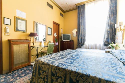 a bedroom with a bed and a desk and a window at Hotel Celio in Rome