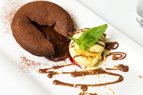 a plate of food with a chocolate doughnut and ice cream at Grami Hotel Sofia in Sofia