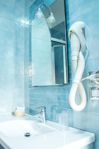 a bathroom with a white hairdryer hanging above a sink at Hotel Ginevra in Poggiomarino