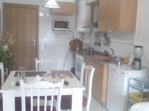 una cocina con una mesa pequeña y una mesa y sillas blancas. en Apartamento de playa, en Boiro