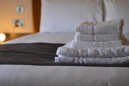 a white towel laying on top of a white bed at Q8 Boutique Hotel in Portsmouth