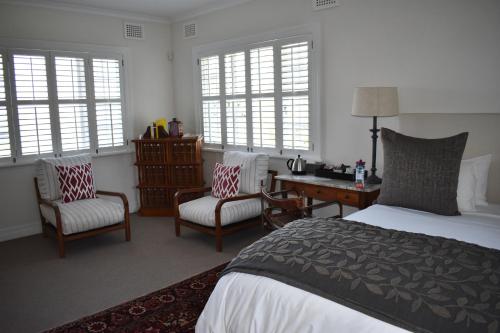 a bedroom with a bed and two chairs and a desk at Southey House in Kloof