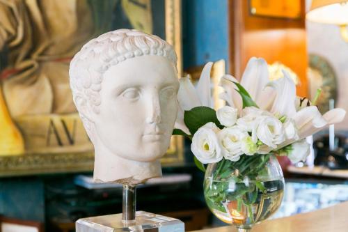 a statue of a head next to a vase of flowers at Hotel Celio in Rome