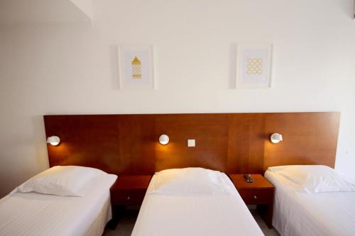 two beds in a hotel room with white sheets at Hospedaria Buganvilia Alvor in Alvor