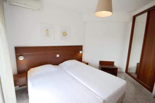 a bedroom with a white bed with a wooden headboard at Hospedaria Buganvilia Alvor in Alvor