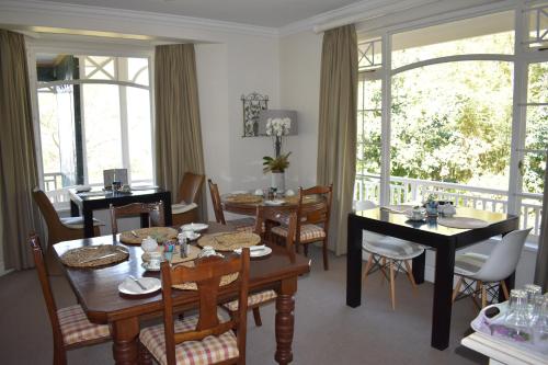 a dining room with tables and chairs and windows at Southey House in Kloof