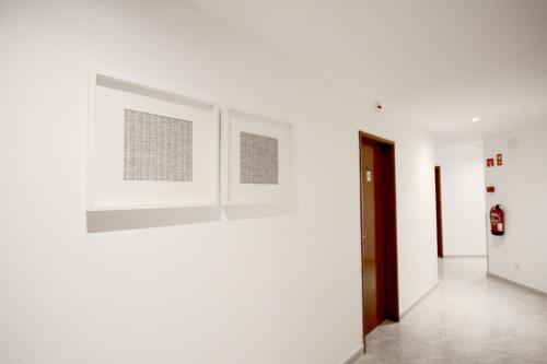 a hallway with white walls and paintings on the wall at Hospedaria Buganvilia Alvor in Alvor