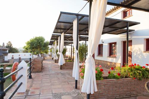 a patio with white umbrellas and flowers at Hotel Cortijo del Arte - Caminito del Rey in Pizarra