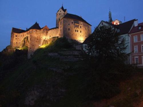 a large castle sitting on top of a hill at night at Penzion Ve Skale in Loket