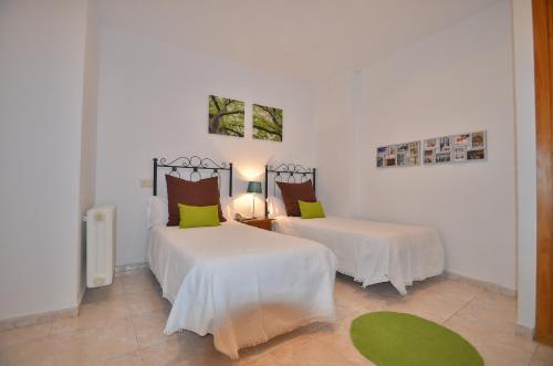 um quarto com 2 camas com lençóis brancos e almofadas verdes em Residencia Ziri em Granada