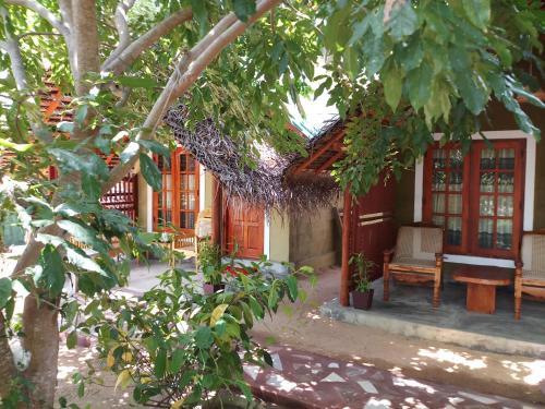 a house with red doors and a chair and trees at Inn On The Bay in Pasikuda