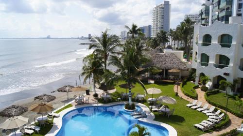 an aerial view of a resort with a swimming pool and the ocean at Playa Caracol Hotel & Spa in Veracruz