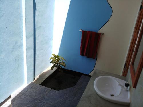 a bathroom with a sink and a toilet and a plant at Inn On The Bay in Pasikuda